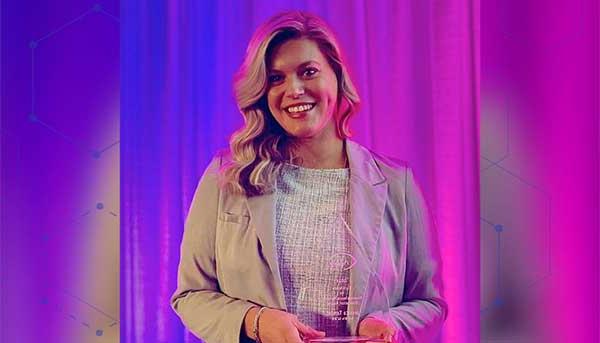 Jessica Tambe holding glass aware in front of a colorful background